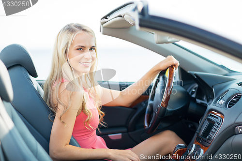 Image of happy young woman driving convertible car