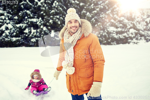 Image of happy man carrying little kid on sled in winter