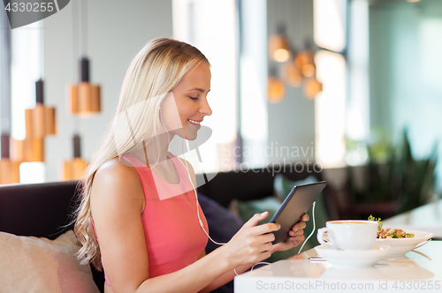 Image of happy young woman with tablet pc at restaurant