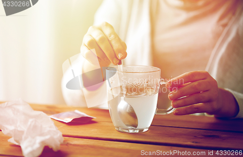 Image of woman stirring medication in cup with spoon