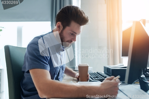 Image of creative male office worker with coffee writing