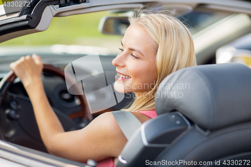 Image of happy young woman driving convertible car