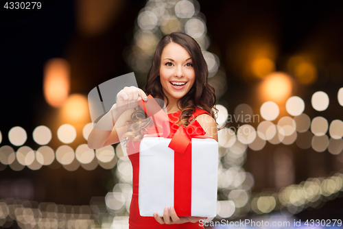 Image of woman with gift box over christmas tree lights