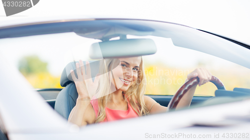 Image of happy young woman driving convertible car