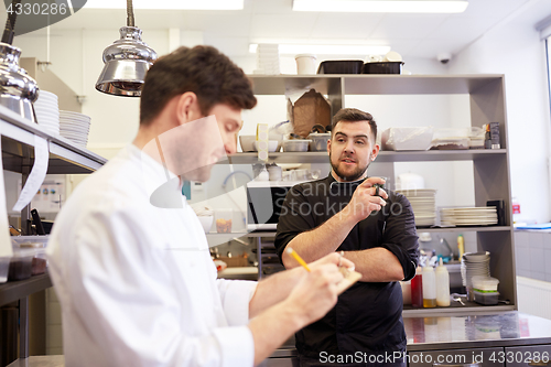 Image of happy smiling chef and cook at restaurant kitchen