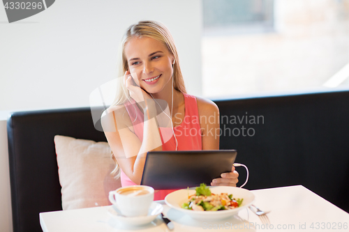 Image of happy young woman with tablet pc at restaurant