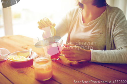 Image of close up of woman adding lemon to tea cup