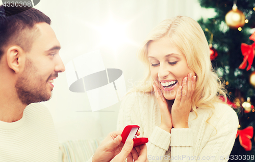 Image of man giving woman engagement ring for christmas