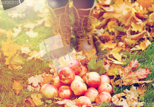 Image of woman feet in boots with apples and autumn leaves