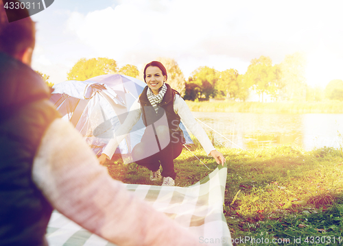 Image of happy couple with picnic blanket at campsite