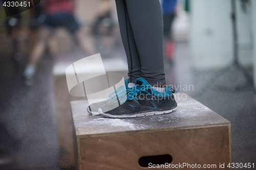 Image of black woman is performing box jumps at gym