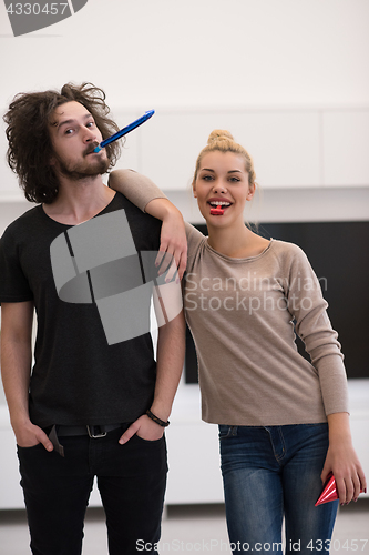 Image of couple in party hats blowing in whistle