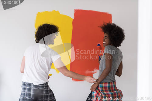 Image of multiethnic couple painting interior wall