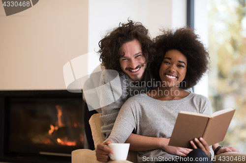 Image of multiethnic couple hugging in front of fireplace