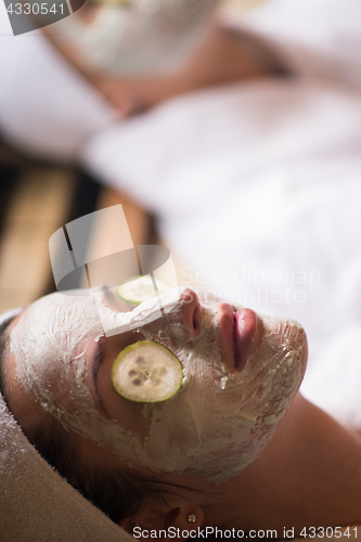 Image of woman is getting facial clay mask at spa