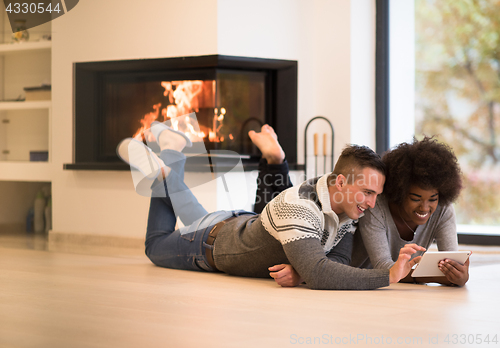 Image of multiethnic couple using tablet computer on the floor