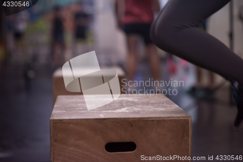 Image of black woman is performing box jumps at gym