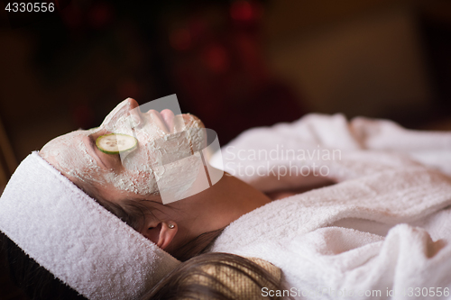 Image of woman is getting facial clay mask at spa