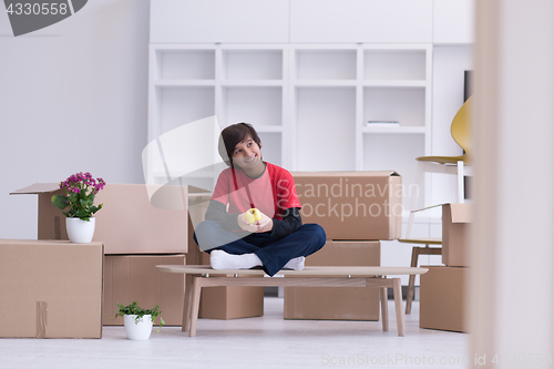 Image of boy sitting on the table with cardboard boxes around him