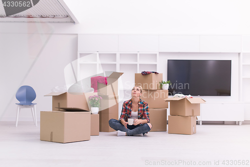 Image of woman with many cardboard boxes sitting on floor