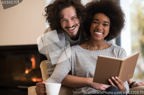 Image of multiethnic couple hugging in front of fireplace