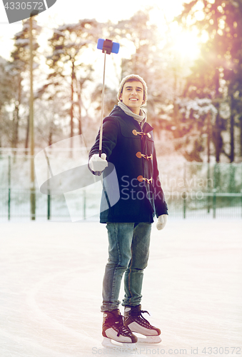 Image of happy young man with smartphone on ice rink
