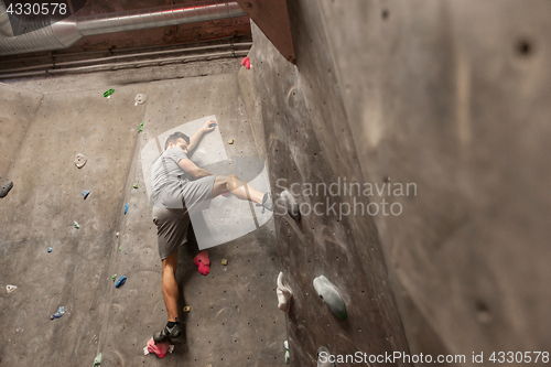 Image of young man exercising at indoor climbing gym wall