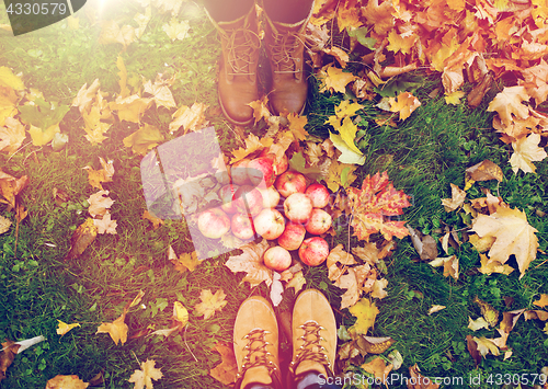 Image of feet in boots with apples and autumn leaves