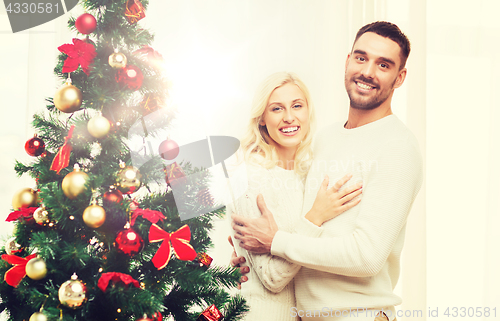 Image of happy couple hugging near christmas tree at home