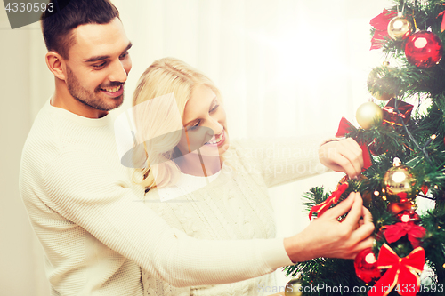 Image of happy couple decorating christmas tree at home