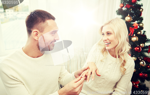 Image of man giving engagement ring to woman for christmas