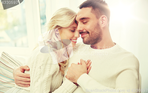 Image of happy couple covered with plaid on sofa at home