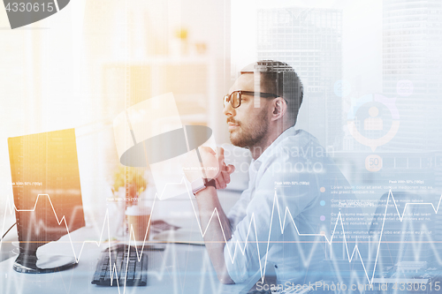 Image of businessman in glasses sitting at office computer