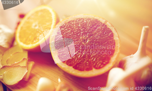 Image of citrus fruits, ginger and garlic on wood