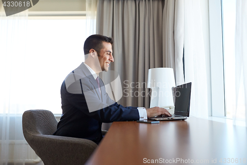 Image of businessman typing on laptop at hotel room
