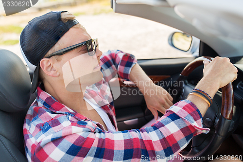 Image of happy young man driving convertible car