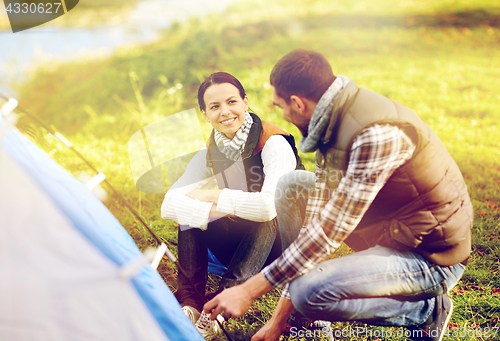 Image of happy couple setting up tent outdoors