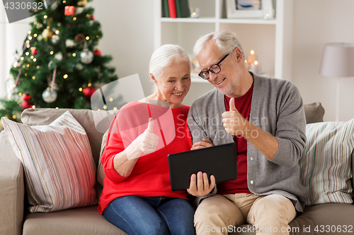 Image of happy senior couple with tablet pc at christmas