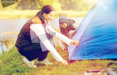 Image of happy mother and son setting up tent outdoors