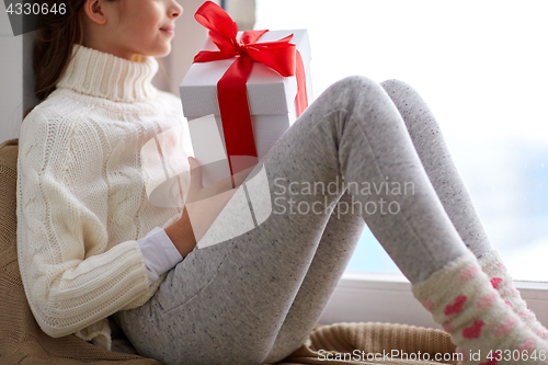 Image of girl with christmas gift sitting on sill at home