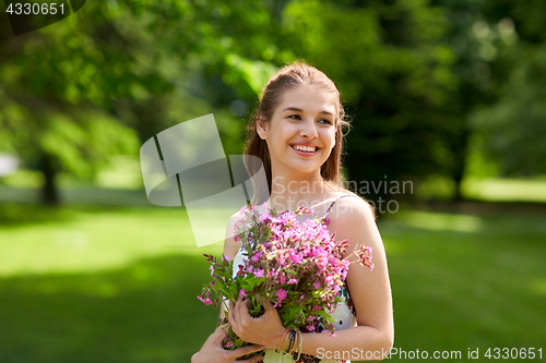 Image of happy young woman with flowers in summer park
