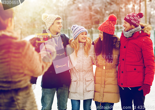 Image of happy friends taking picture with smartphone