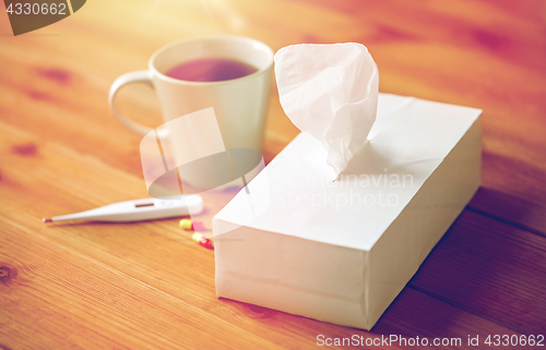 Image of cup of tea, paper wipes and thermometer with pills