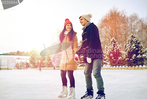 Image of happy couple ice skating on rink outdoors