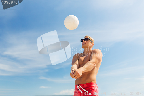 Image of young man with ball playing volleyball on beach