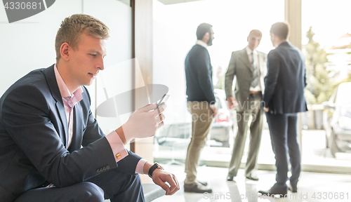 Image of Businessman using smart phone while sitting in waiting room.