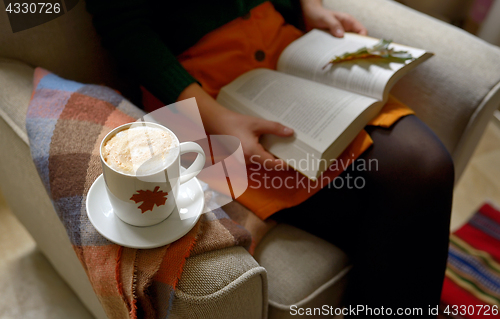 Image of Cup of cappuccino and girl reading a book