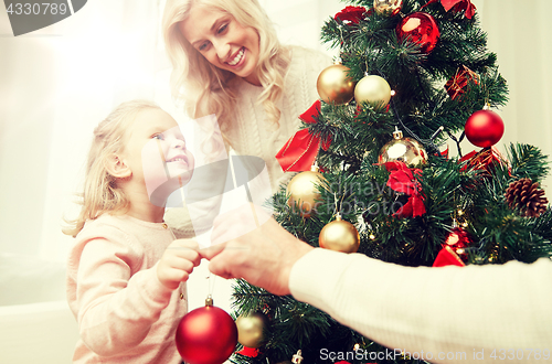 Image of happy family decorating christmas tree at home