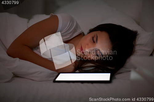 Image of woman with tablet pc sleeping in bed at night