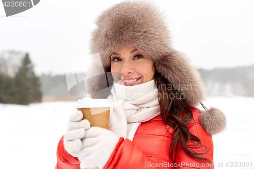 Image of happy woman in winter fur hat with coffee outdoors